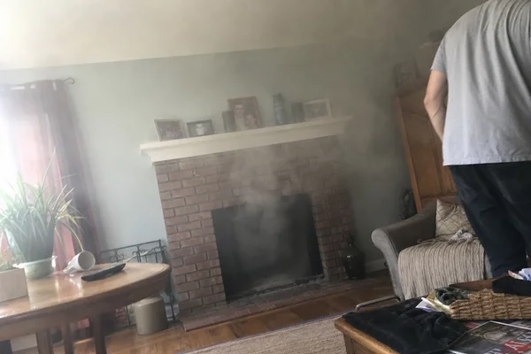 Smoke drifting out of a brick fireplace back into a living room