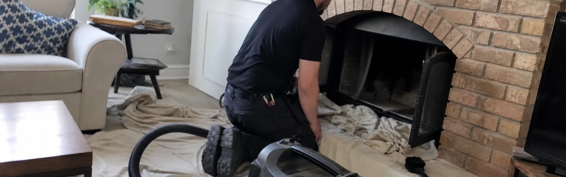 Chimney sweep laying drop cloths near a brick fireplace