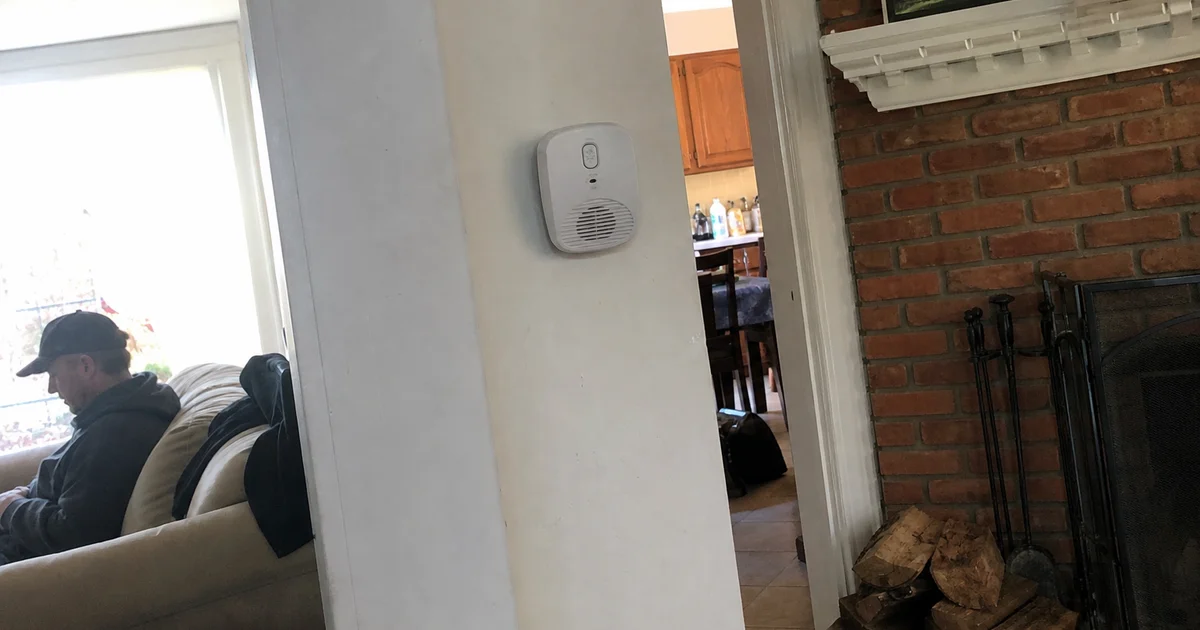 Carbon monoxide detector on a hallway wall near a living-room fireplace