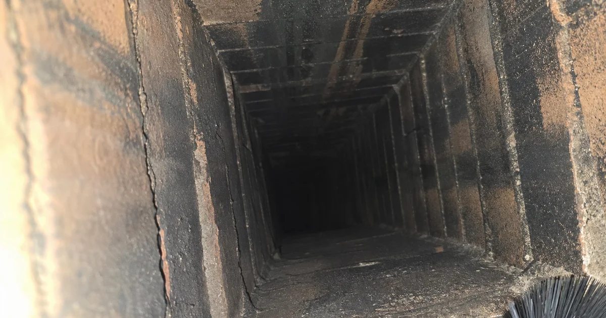 Close-up inside a brick chimney flue showing dark creosote buildup