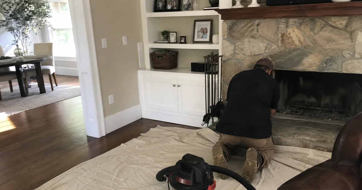 CSIA technician laying drop cloths and setting up a HEPA vacuum by a fireplace