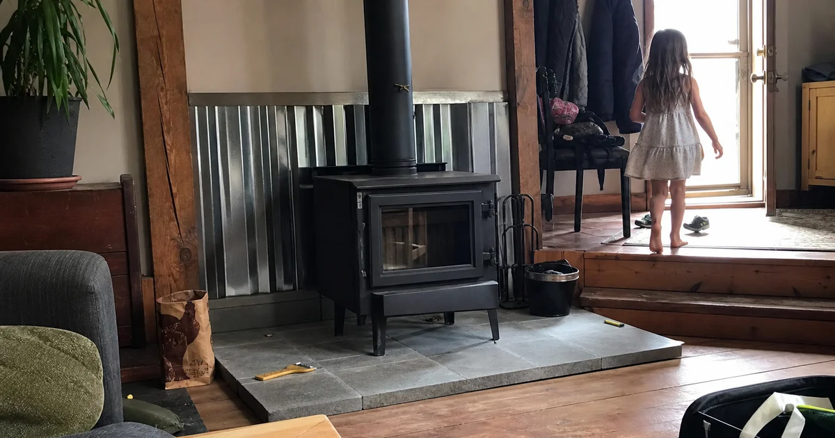 Freshly installed wood stove on a hearth pad with new stovepipe