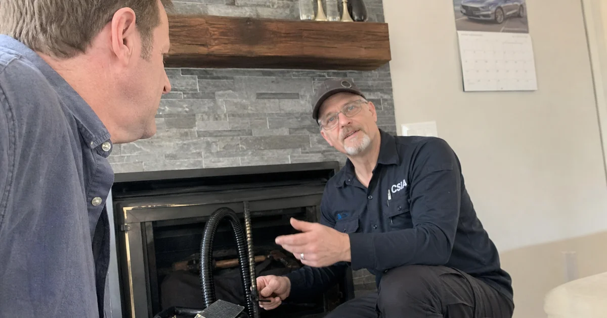 Homeowner and technician discussing chimney maintenance schedule beside a fireplace