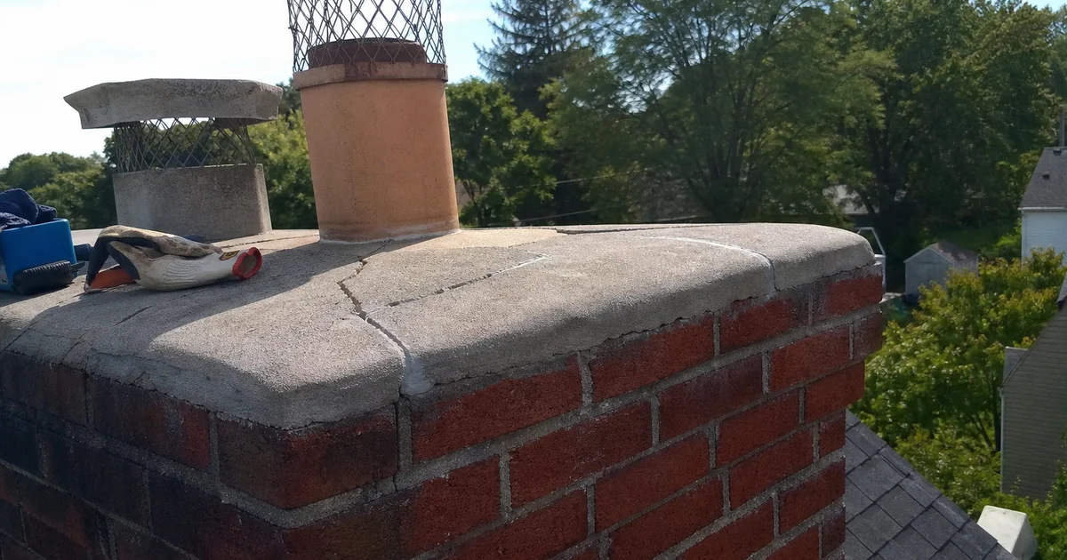 Top of a brick chimney showing a cracked concrete crown