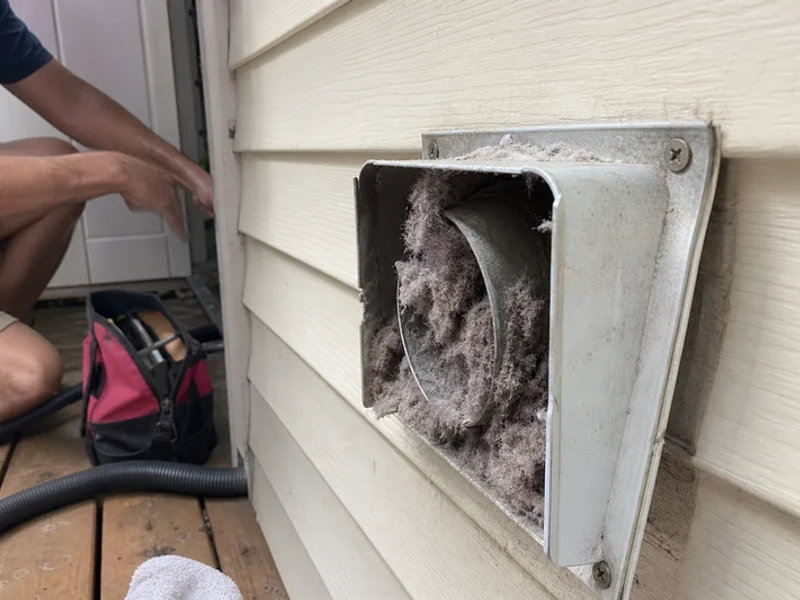 Heavy lint buildup at an exterior dryer vent hood before cleaning