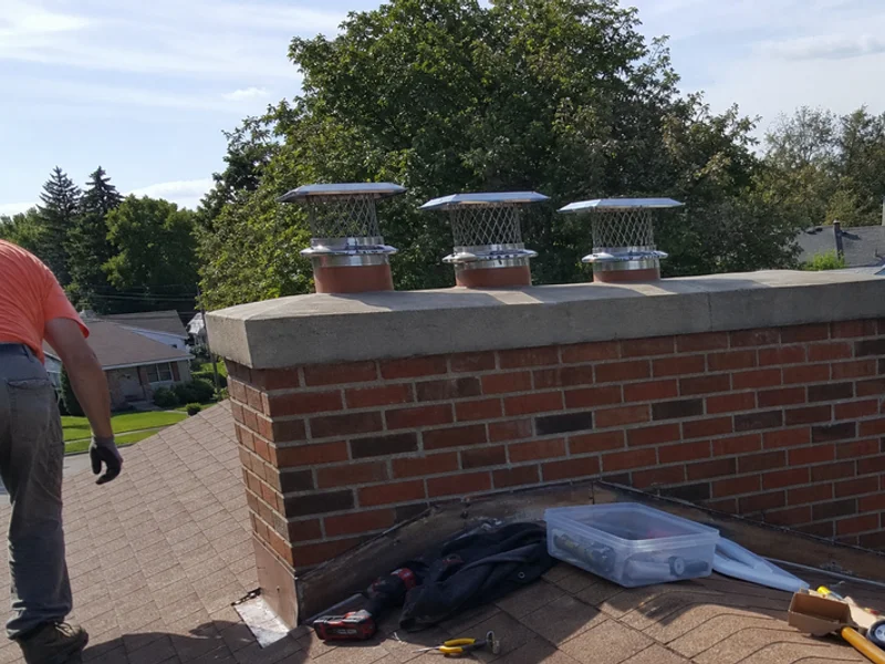 Multi-flue stainless steel chimney cap on a wide brick chimney
