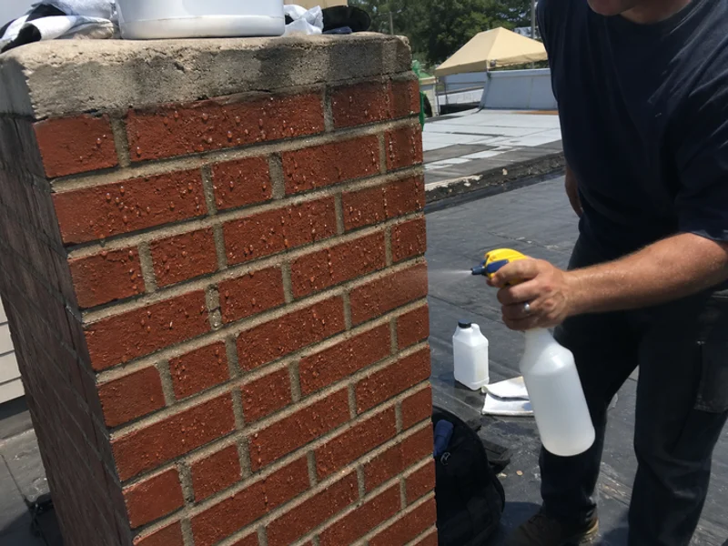 Technician spraying Silane-Siloxane waterproofing on a chimney