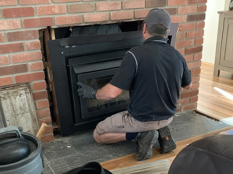 Wood-burning fireplace insert being fitted into an existing masonry fireplace