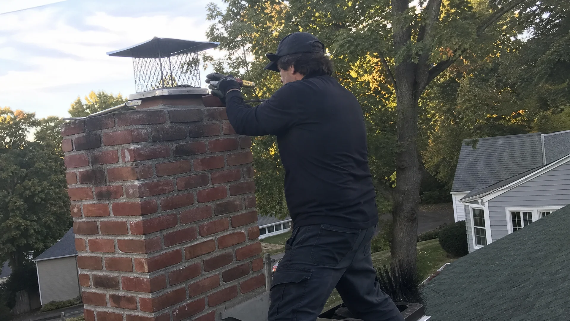 CSIA-certified chimney sweep repairing a brick chimney on a New England home