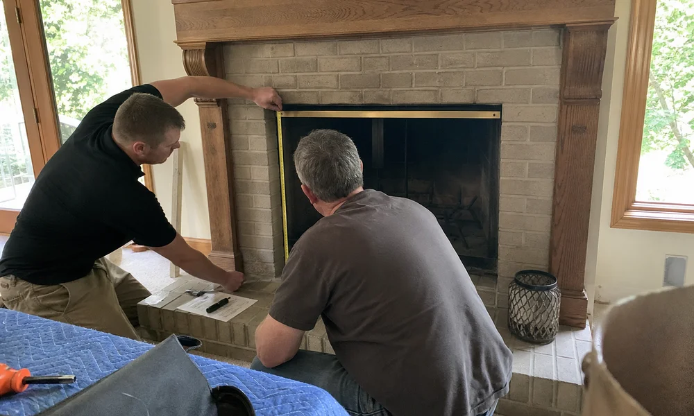 Homeowner and installer measuring a fireplace opening for an insert