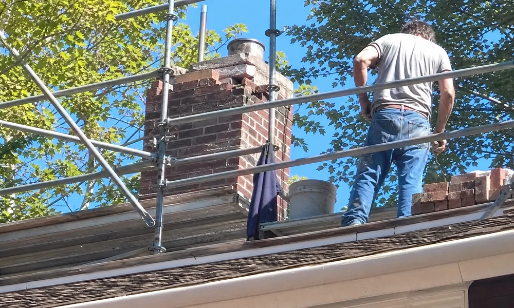 Partial chimney rebuild above the roofline with matched historic brick
