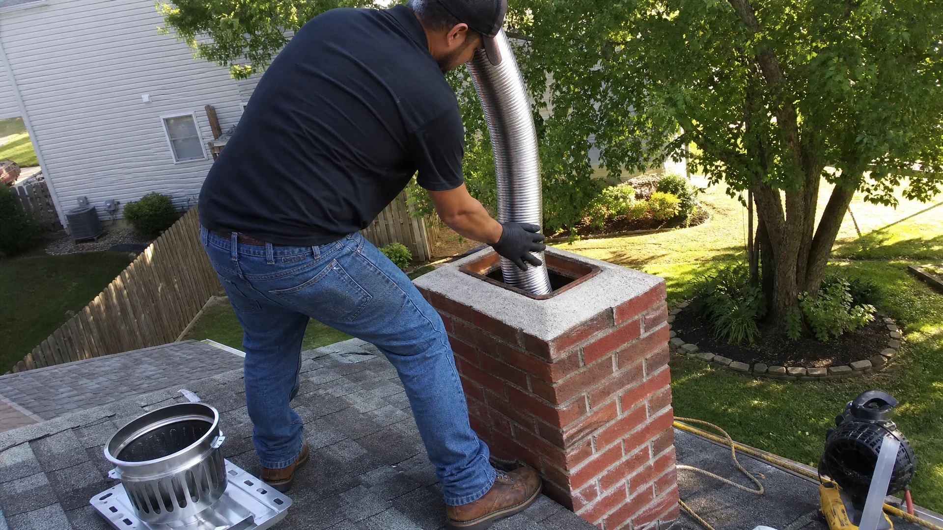 Technician feeding a flexible stainless steel liner into a brick chimney