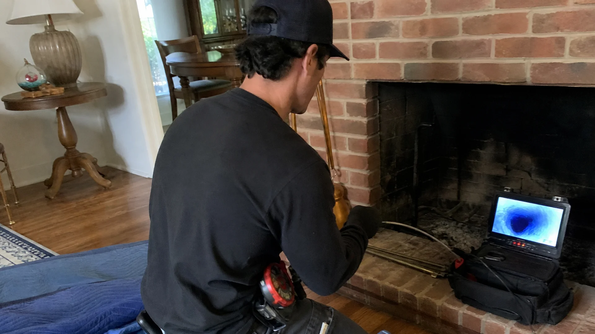 Chimney technician performing a video scan of a flue with the monitor visible