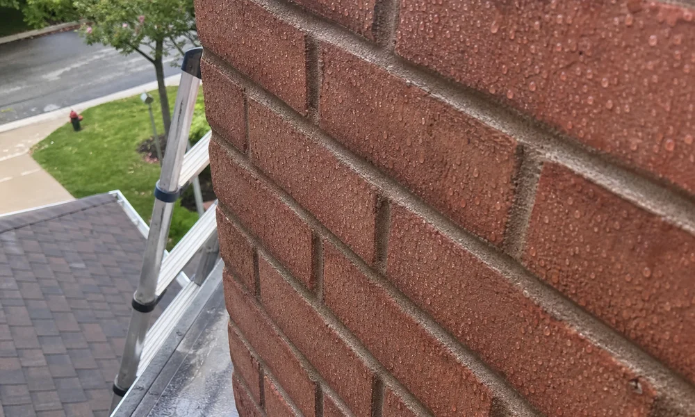 Water beading on a treated brick chimney surface after rain