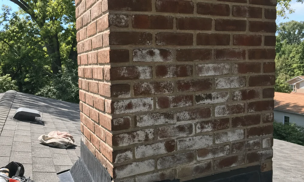White efflorescence staining on the side of a brick chimney